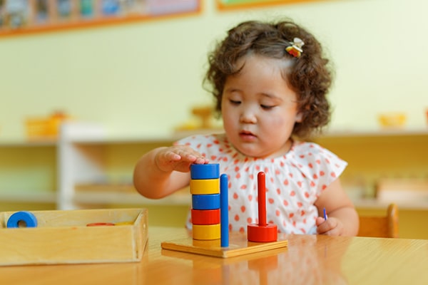 child placing round rings on three vertical pegs